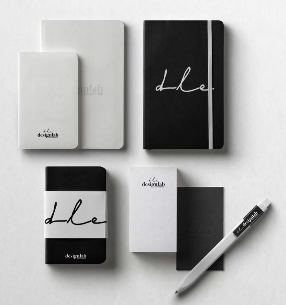 Black and white notebooks with dle on them, cards and a pen